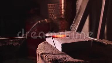 铁匠用大锤在铁砧上缓慢地敲击铁棒。